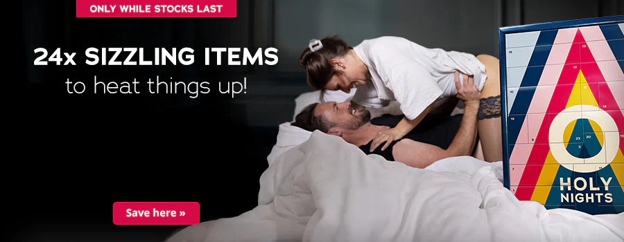 There is a couple shown on the advertisement. A man is lying on his back on a bed and a woman is leaning over him. They are smiling at each other. The man is wearing a black T-shirt and the woman is wearing a white one. She is also wearing black lace stockings. The Advent calendar in a colourful design and the text “HOLY NIGHTS” are prominently displayed. The sentence: “24x sizzling items to heat things up!” can be seen above this in white letters. There is a red banner at the top with the words “Only while stocks last”. There is another red banner at the bottom with the words “Save here »”.