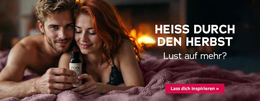 Paar liegt eng umschlungen auf rosa Bettdecke, hält ein Massageöl in der Hand; Kaminfeuer im Hintergrund, Text „Heiss durch den Herbst – Lust auf mehr?“ und Button „Lass dich inspirieren“