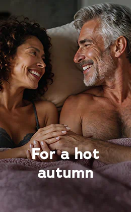 A couple are lying next to each other in bed. They are smiling at each other. There is a woman with dark curly hair on the left-hand side. She is wearing a lace bra. There is a topless man on the right-hand side. He has grey hair and a beard. Text: “For a hot autumn”. Red button: “Discover pleasure boosters”.